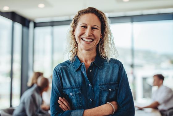 female employee smiling brightly at the camera in a denim shirt